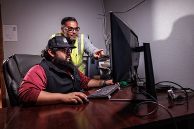 Two Frontier Waste Solutions operations team members viewing data on a computer screen.
