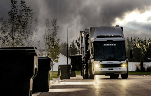 McNeilus refuse truck with AI material contamination detection technology collecting waste in a neighborhood.