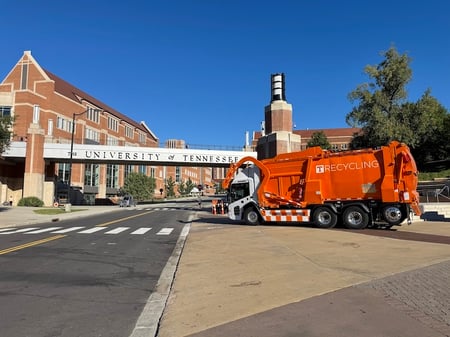 University of Tennessee Knoxville's McNeilus Volterra ZFL electric refuse vehicle in front of a University sign