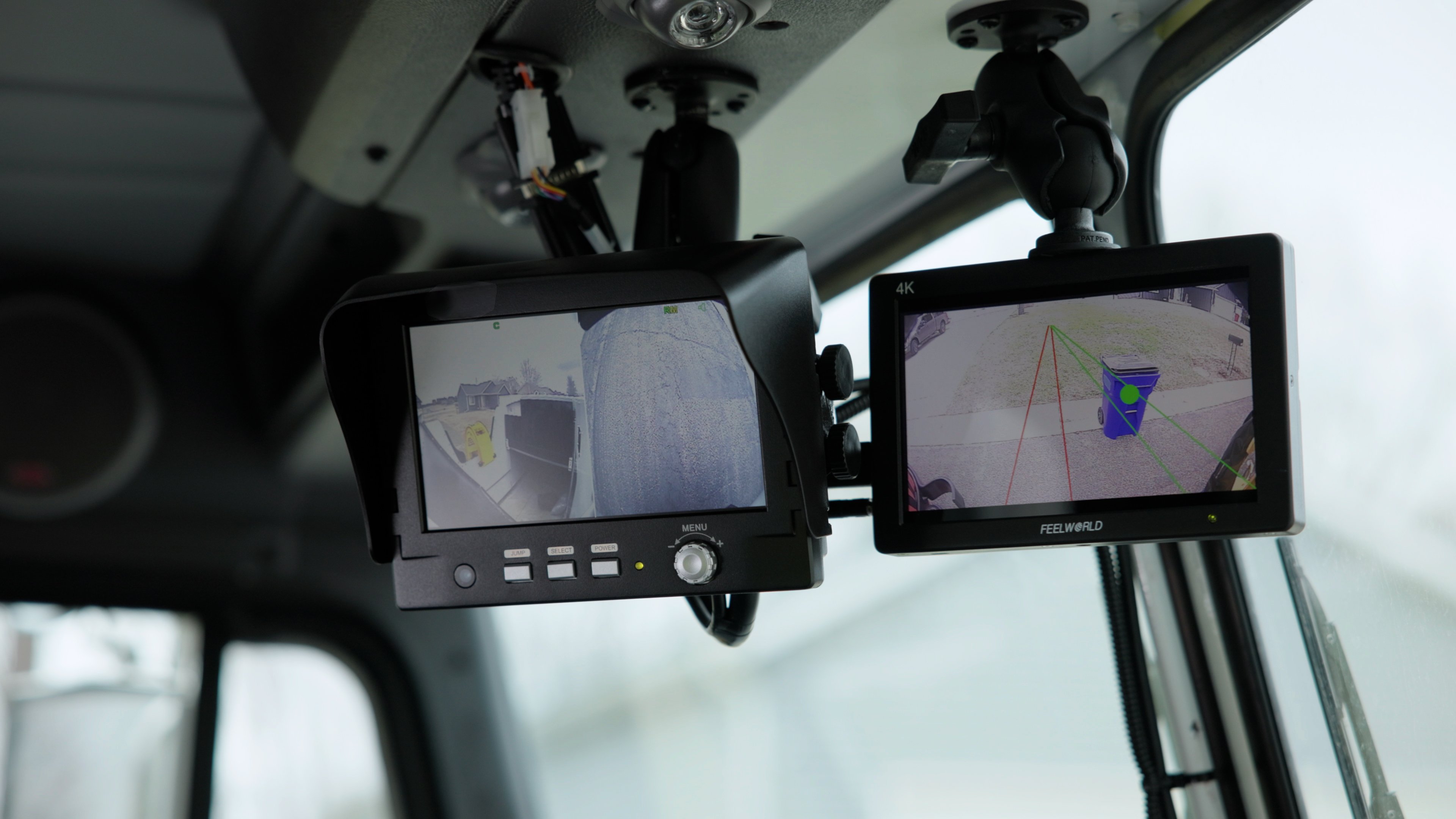 Two small screens on the inside of a garbage truck that help see the lineup to a garbage can.