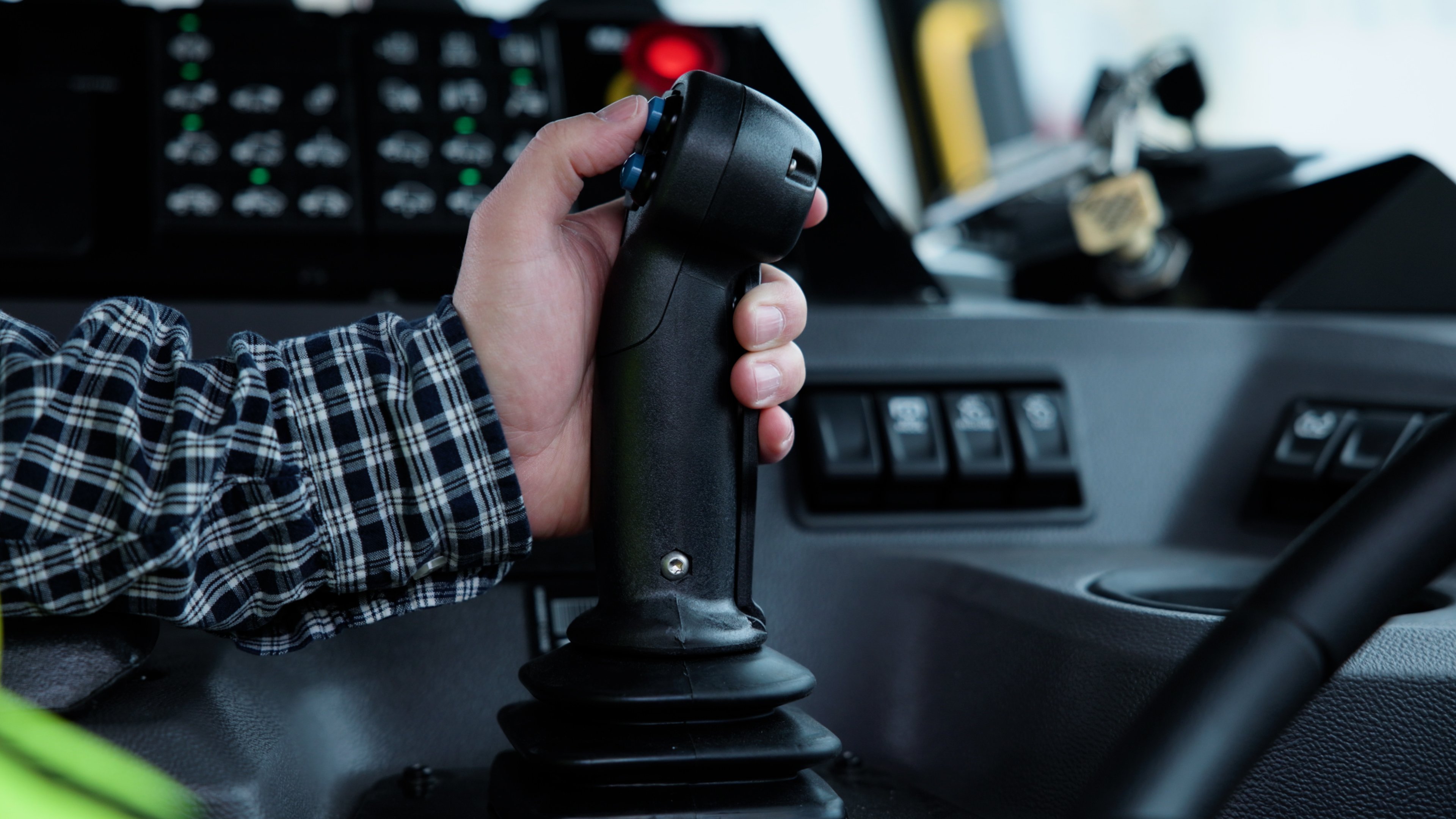 A close up of a person operating a joy stick control inside of a garbage truck.